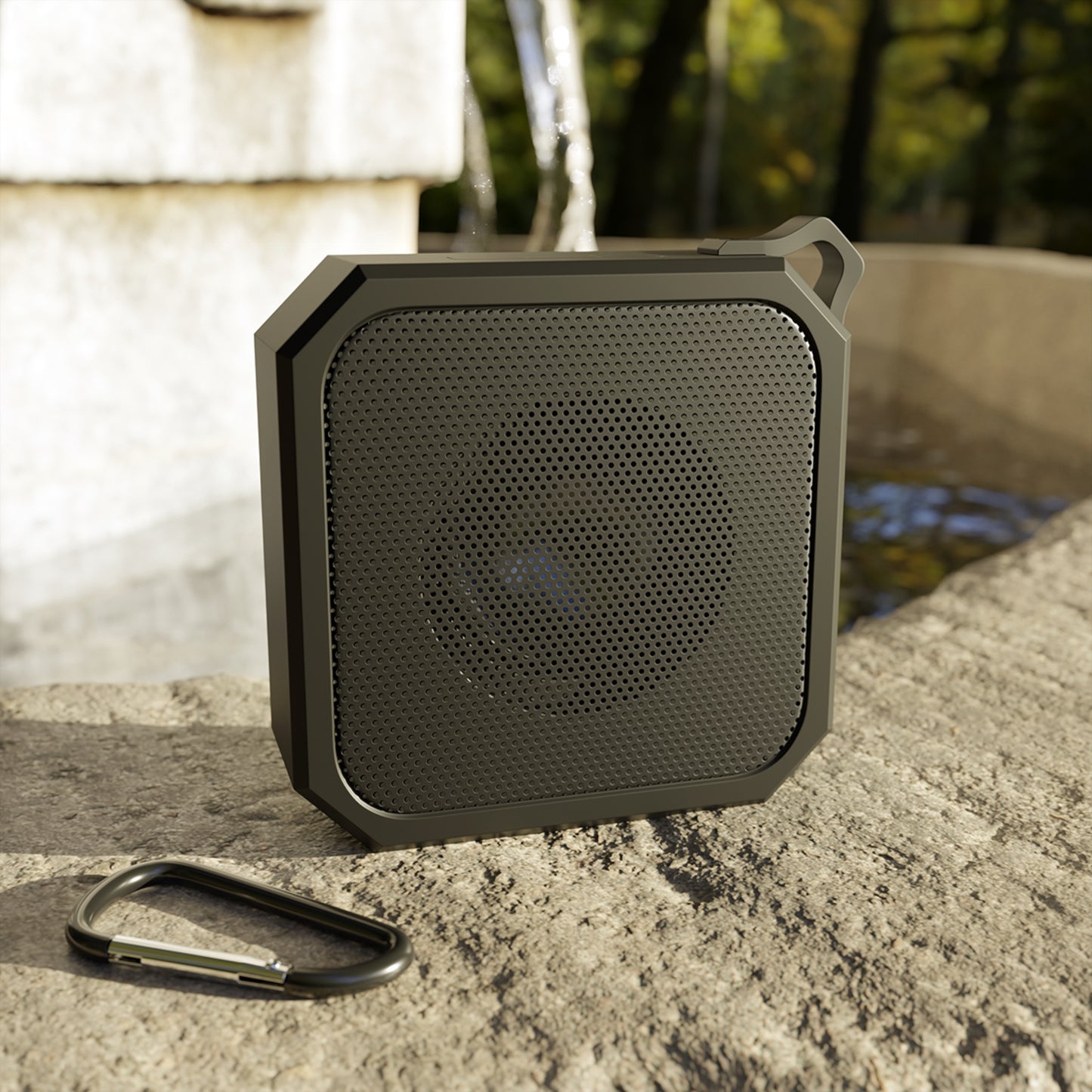 Black portable speaker on a stone surface with a natural background