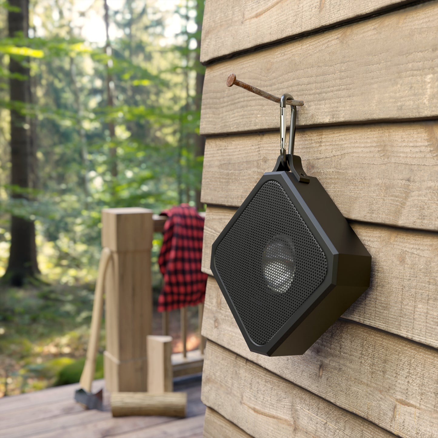 Black outdoor speaker attached to a wooden wall with a forest background